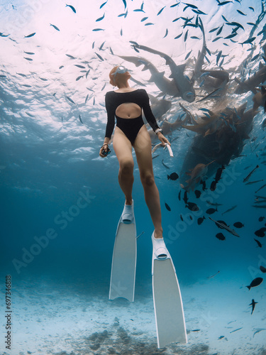 Woman dives along the nurse sharks in Maldives. Underwater view of the girl swimming with shark in ocean