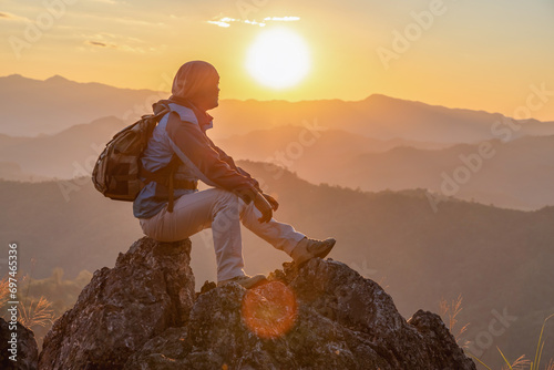 Hiker with backpack sitting on top mountain sunset background. Hiker man hiking living healthy active lifestyle.