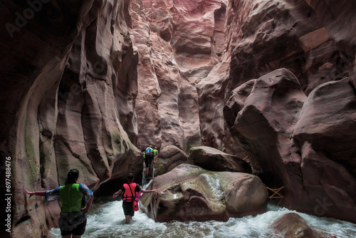 Extreme tourists walk along the Mujib River, flowing between high cliffs along the tourist route in the Mujib River canyon in Wadi al-Mujib in Jordan