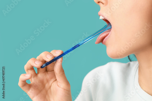 Young woman with tongue scraper on blue background