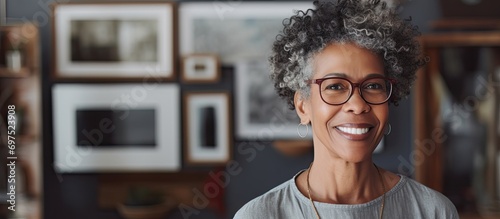 Confident senior African American woman smiling with empty frame in art studio.