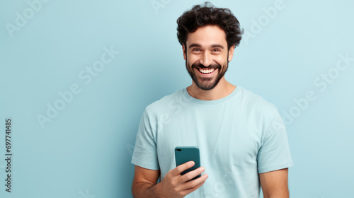 Young man smiling and holding his smartphone on a colored background