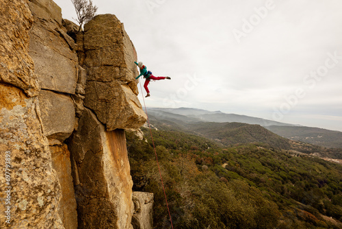 Person climbing in high mountains with yellow jacket rope and helmet in nature, confidence and risk, safety