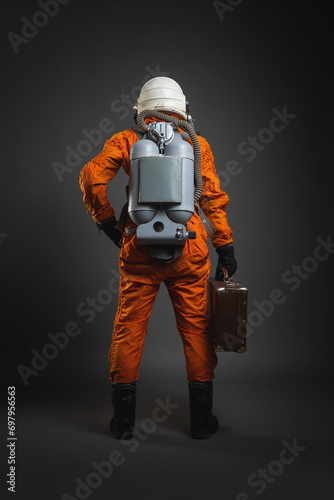 Astronaut is standing in the space suit and helmet on the gray background. Back view.