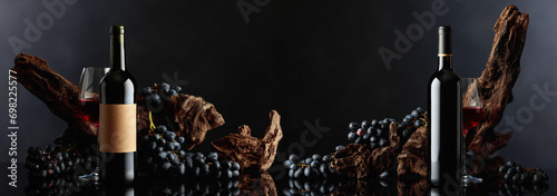 Bottles of red wine with old weathered snag and blue grapes.