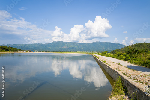 A village path in the middle of a lake and rice fields, Asia, Vietnam, Tonkin, Dien Bien Phu, in summer, on a sunny day.