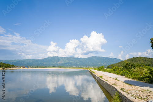 A village path in the middle of a lake and rice fields, Asia, Vietnam, Tonkin, Dien Bien Phu, in summer, on a sunny day.