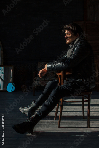 handsome man in black clothes sitting on a chair
