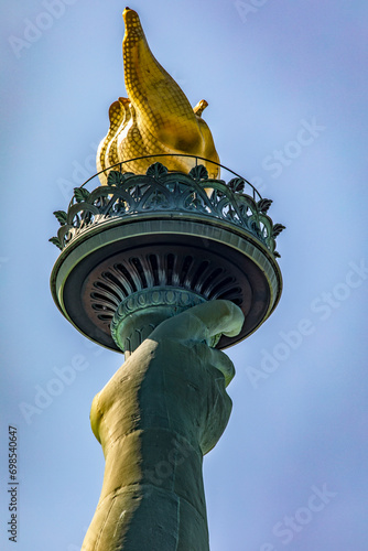 Photo of the Statue of Liberty hand holding her torch on a sunny day in Manhattan, known as the lady of New York City USA.