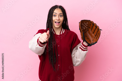 Teenager player with baseball glove isolated on pink background surprised and pointing front