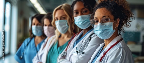 Diverse team of doctors and nurses posing together, wearing masks in a clinic.