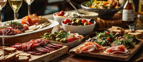 Assorted appetizers including antipasti, charcuterie, snacks, meat and cheese platter, spicy olives, salmon carpaccio, and tomato salad.