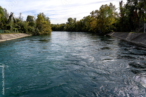 runoff basin from the Vaprio d'adda hydroelectric power plant, whose waters flow azure between wooded banks 