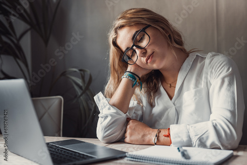 Exhausted young Caucasian female worker sit at desk massage neck suffer from strain spasm muscles. Tired unwell woman overwhelmed with computer work sedentary lifestyle struggle with back pain or ache