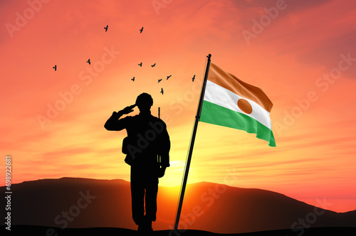Silhouette of a soldier with the Niger flag stands against the background of a sunset or sunrise. Concept of national holidays. Commemoration Day.