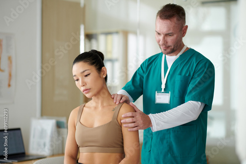Therapist palpating and massaging neck and shoulders of female patient