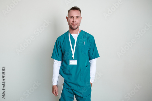 Portrait of smiling mature physiotherapist with clipboard standing against white wall