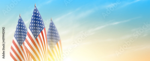 Banner with United State of America flags. US flags isolated on cloudy sky at sunrise. Realistic flags for decoration USA events. Symbol of United States of America. Vector illustration.