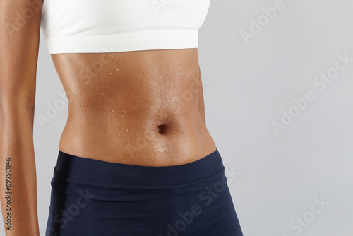 Fitness workout, woman sweaty abdomen, drops of sweat on skin belly Close up, African latin American female athlete in sportswear, Sportswoman do exercise in gym to improve abdominals, health and diet