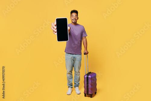 Traveler man wears casual clothes hold bag blank screen mobile cell phone isolated on plain yellow background. Tourist travel abroad in free spare time rest getaway. Air flight trip journey concept.