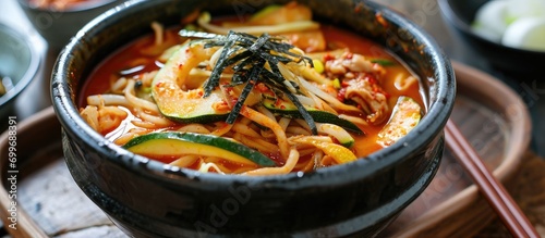 Korean noodle soup with handmade fresh noodles cooked in anchovy sauce, enhanced with zucchini, potatoes, and seafood.