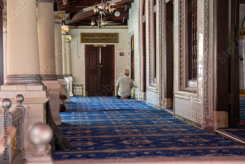 A person in solitary prayer in a peaceful mosque interior with ornate decor.