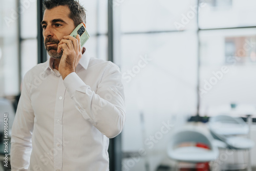 Successful businessman negotiating a deal over the phone in office.