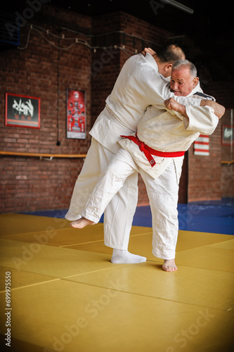 Judo sensei master instructor in traditional gi kimono demonstrate judo throw technique on tatami