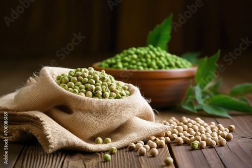 Heap of uncooked dried chickpeas in a burlap sack alongside raw green chickpea pods and a plant on a wooden table