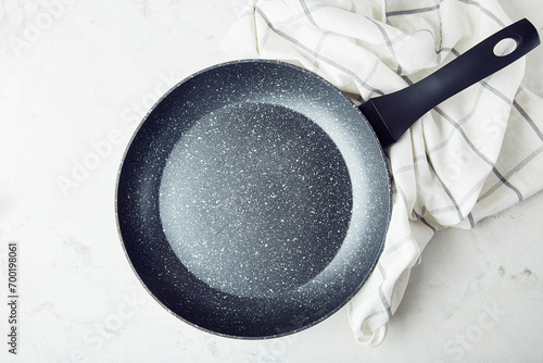 Black non-stick stainless steel frying pan on a marble background. Template.