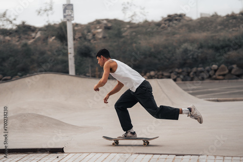 young man with white t-shirt skating in a skate park