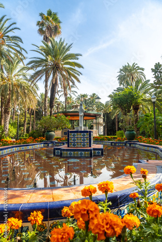 Templete or pergola and the fountain with flowers in the palm grove park in the city of Elche. Spain