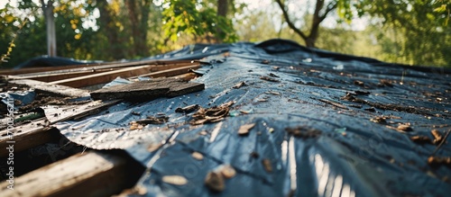 Roof damaged by storm, covered with black tarp after violent thunderstorm.