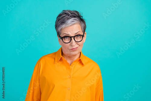 Photo of suspicious distrustful business woman old grandmother raise eyebrows wear orange shirt isolated on aquamarine color background