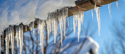 Close-up of icicles hanging from a snow-covered roof gutter.