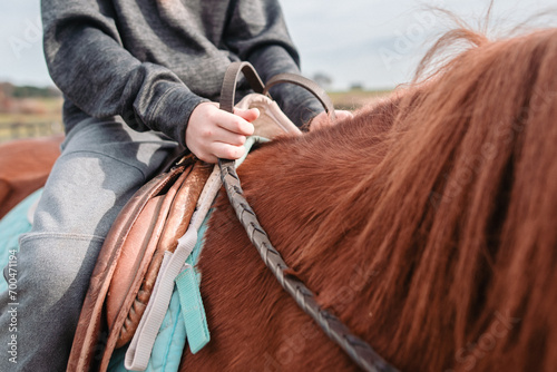 Close up of boy on horseback holding reins in hands