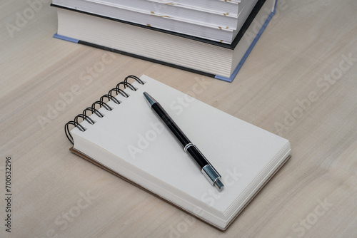 Notes z długopisem leży na biurku obok podręczników 