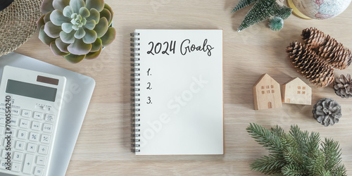 2024 goals new year resolutions on blank note book memo reminder wish list of yearly planner, action plan for work-life balance, good financial health, happy home family, travel aims on office desk