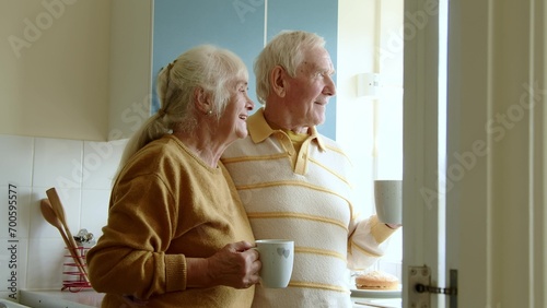 Happy senior couple drinking coffee or tea on home kitchen