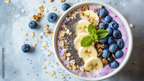 Сlose-up of a healthy vegan breakfast. A plate with healthy superfood - fresh berries, fruit yogurt, chia seeds, granola and banana slices on pastel table. 