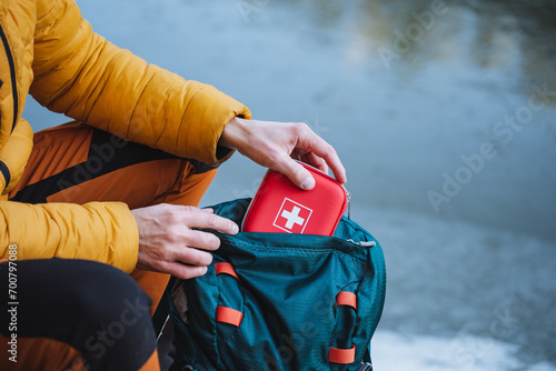 A guy puts a first aid kit in a backpack, packing things for a hike, safety in a winter trip, trekking in the mountains. personal first aid kit.
