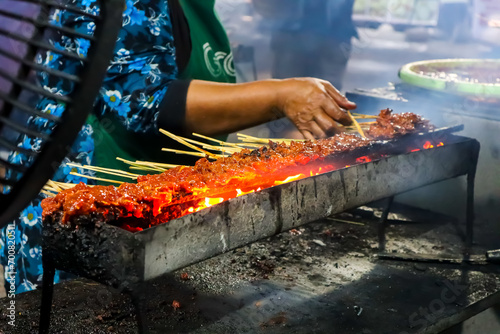 Hand of indonesian woman preparing satay in traditional charcoal satay grill