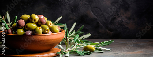 Fresh olives in a wooden bowl on a dark stone table. Black and green olives