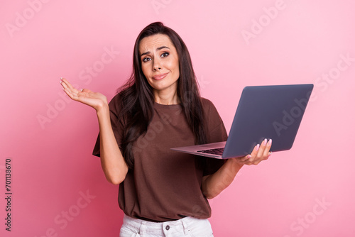 Photo of young funny woman working indifferent shrug shoulders ignoring boss messages using laptop isolated on pink color background
