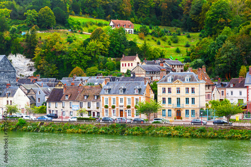 The coast of the Seine River in France in the suburbs of Rouen with beautiful private houses and dense green vegetation and mountains.