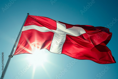 Danish flag against the sun in a clear sky. 