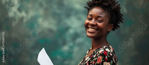 With a beaming smile and confident posture a woman holds up a paper proclaiming PERMANENT JOB The floral pattern of her dress contrasts with the formality of the employment milestone. Creative Banner