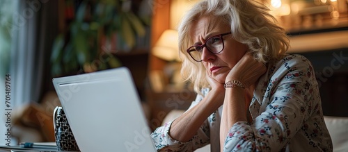 Pretty middle aged woman working late in the day on a laptop computer at home running a business from home working remotely getting frustrated. Creative Banner. Copyspace image
