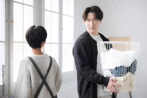 Husband carrying laundry and wife frustrated because of slow housework
