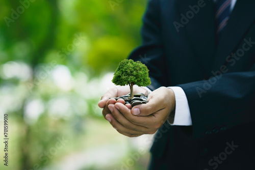 Green investment to a sustainable environment. Businessman holding coins and planting trees. Business company or organization that cares about responsible environmental, social, and governance.